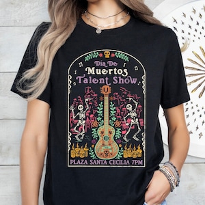 May include: A white ceramic mug with a black handle and the text "But First, Coffee" in a bold, black font. The mug is set against a blurred background, highlighting its clean design.