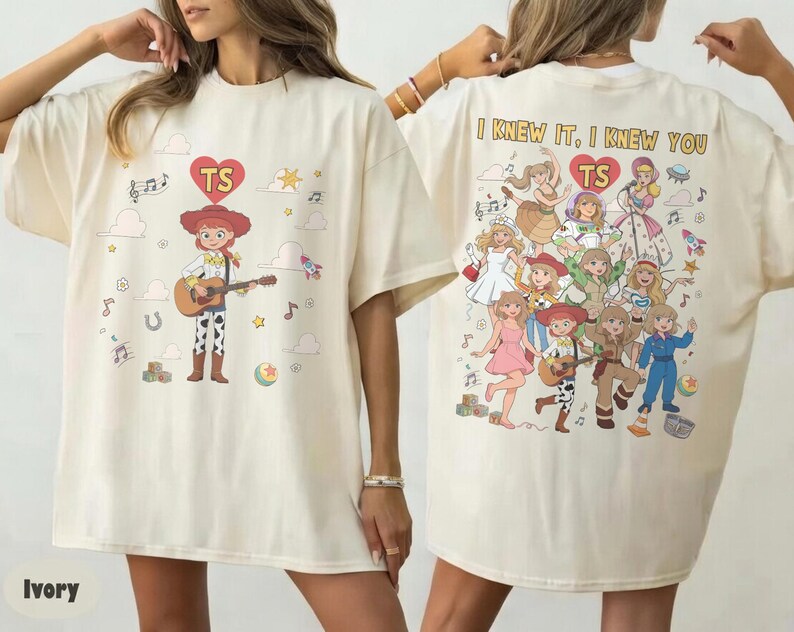May include: An ivory t-shirt featuring a graphic of a cowgirl playing a guitar on the front and a collage of various illustrated characters with the text "I KNEW IT, I KNEW YOU" and "TS" inside a red heart on the back, with scattered musical notes.