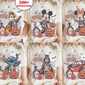 Op de afbeelding: Crèmekleurige t-shirts met Halloween-thema's. De ontwerpen tonen personages als Chip, Mickey, Minnie, Stitch, Darth Vader en Lightning McQueen, allemaal afgebeeld als skeletten met pompoenen en het woord "BOO!" in een spinnenweb.