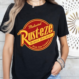 Könnte beinhalten: Schwarzes T-Shirt mit einem roten und gelben Logo, auf dem "Medicated Rust-eze Bumper Ointment Rear End Formula" steht.