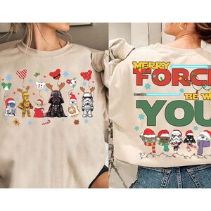 May include: Beige sweatshirt with Star Wars characters in Christmas outfits. The front shows characters with reindeer antlers and balloons. The back says "Merry Force Be With You" with lightsabers and more characters.