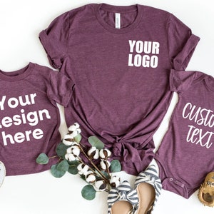 May include: Three maroon t-shirts with white text. The largest shirt says "Your Logo". The medium shirt says "Your design here". The smallest shirt says "Custom Text".