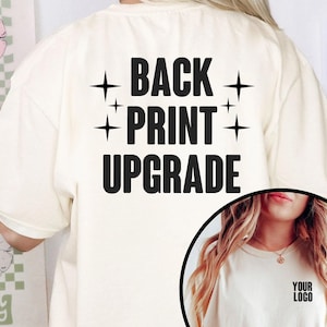 Puede incluir: Camiseta color crema con el texto "BACK PRINT UPGRADE" en letras negras en negrita, acentuado por cuatro estrellas. Una imagen más pequeña muestra una camiseta con el texto "YOUR LOGO".