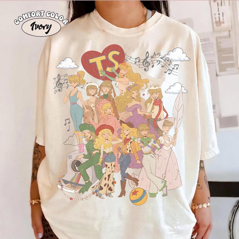 May include: An ivory t-shirt featuring a large graphic print of various cartoon characters in diverse outfits, a red heart with the letters TS, musical notes, and clouds. The text COMFORT COLOR IVORY is printed in a small oval at the top left.