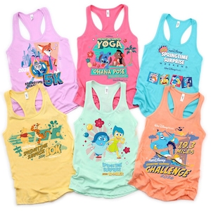 Könnte beinhalten: Eine Auswahl an farbenfrohen Racerback-Tops mit verschiedenen grafischen Designs. Die Tops zeigen Charaktere und Texte im Zusammenhang mit einem Frühlingsereignis, darunter "5K", "10K" und "19.3 Miles". Farben sind Pink, Blau, Gelb und Orange.