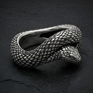 May include: A silver-toned ring shaped like a coiled snake with detailed, textured scales covering the entire band. The head of the snake is positioned at the front, and the interior of the band is clearly stamped with the hallmark 925.