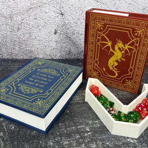 May include: A blue and gold book-shaped box with the quote "A table full of friends is the greatest magic of all." A red book-shaped box with a gold dragon design. A white dice tray holds various colored dice.
