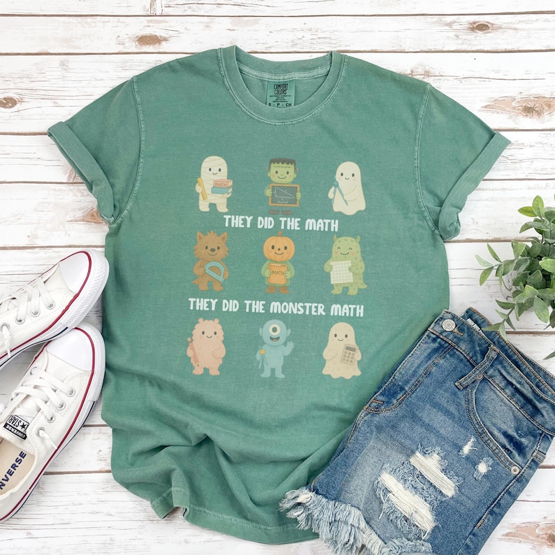 May include: A green t-shirt with the text "THEY DID THE MATH" and "THEY DID THE MONSTER MATH" above and below cartoon monster illustrations. The shirt is paired with denim shorts and white sneakers.