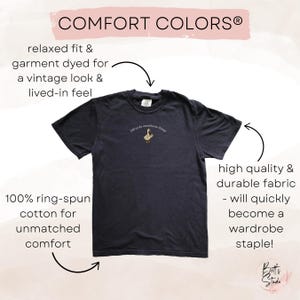May include: A dark navy blue t-shirt with the text "Off to do anesthesia things" above a small embroidered goose. The shirt is made of 100% ring-spun cotton and is garment dyed for a vintage look.
