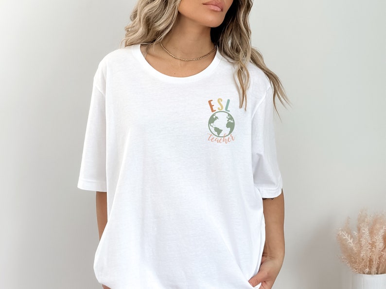 May include: White t-shirt with a graphic of a globe and the text "ESL teacher" in colorful letters.