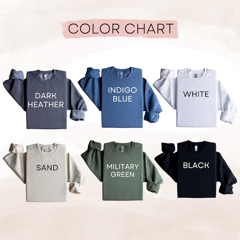May include: A color chart displaying six long-sleeve crewneck sweatshirts in dark heather, indigo blue, white, sand, military green, and black. Each sweatshirt features its corresponding color name printed in bold black or white text on the front.
