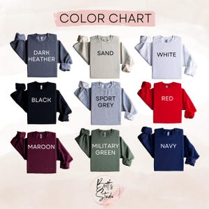 May include: A colour chart displaying nine crewneck sweatshirts in different shades: dark heather, sand, white, black, sport grey, red, maroon, military green, and navy. Each sweatshirt has its colour name in white text.