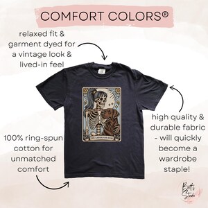 May include: A dark grey t-shirt with a vintage-style illustration of a skeleton holding a dog. The text "The Labrador Mom" is printed below the image. The shirt is made of 100% ring-spun cotton for a relaxed fit and a lived-in feel.