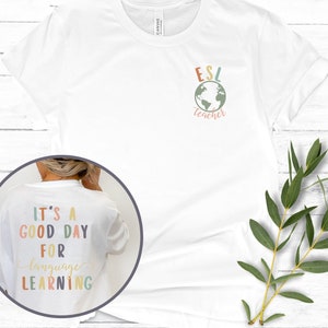 May include: White t-shirt with the text "ESL teacher" and a globe graphic on the front. The back of the shirt has the text "It's a good day for language learning" in colorful letters.