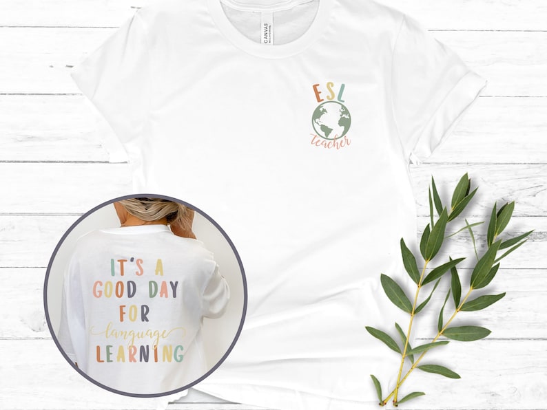 May include: White t-shirt with the text "ESL teacher" and a globe graphic on the front. The back of the shirt has the text "It's a good day for language learning" in colorful letters.
