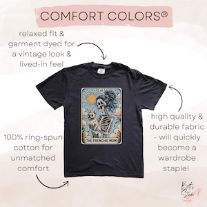 May include: A dark gray t-shirt with a vintage-style illustration of a skeleton holding a small dog. The illustration is on a tarot card with the text "The Frenchie Mom" and the number "89".