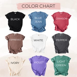 May include: A color chart displays nine t-shirts in various colors: black, blue jean, crimson, espresso, white, pepper, ivory, violet, and light green. Each shirt has its color name printed in white.