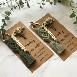 The macrame keychain is attached to a personalizable card. There are real flowers on the card.