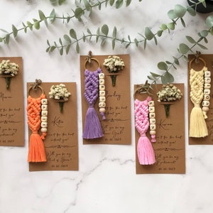 The macrame keychain is attached to a personalizable card. There are real flowers on the card.