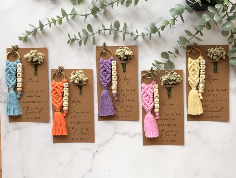 The macrame keychain is attached to a personalizable card. There are real flowers on the card.
