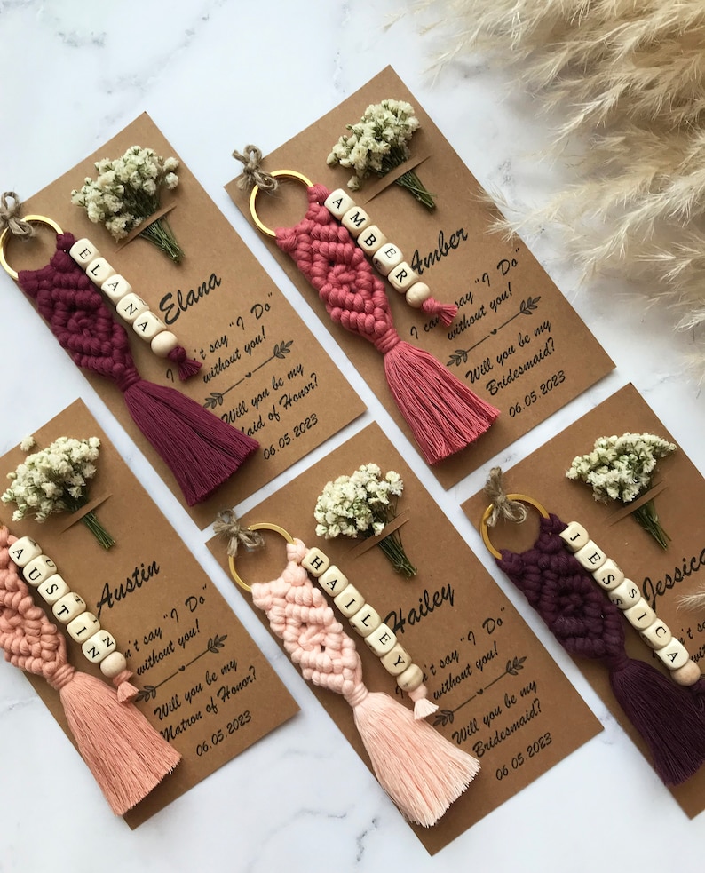 The macrame keychain is attached to a personalizable card. There are real flowers on the card.