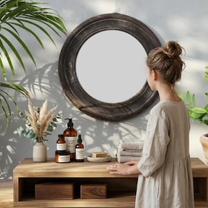Handcrafted round mirror with a reclaimed teak wood frame and smoky black finish, featuring rounded edges and natural wood character. Rustic wall mirror for bedroom, bathroom, living room or entryway. Reclaimed teak mirror, round wooden mirror, black wood mirror, handmade wall decor, rustic home decor, sustainable wood furniture, artisan-crafted mirror.