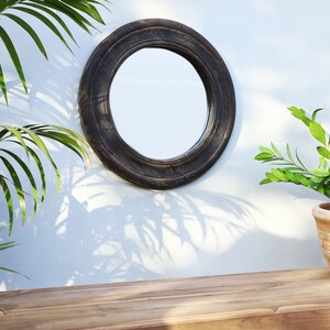 Handcrafted round mirror with a reclaimed teak wood frame and smoky black finish, featuring rounded edges and natural wood character. Rustic wall mirror for bedroom, bathroom, living room or entryway. Reclaimed teak mirror, round wooden mirror, black wood mirror, handmade wall decor, rustic home decor, sustainable wood furniture, artisan-crafted mirror.