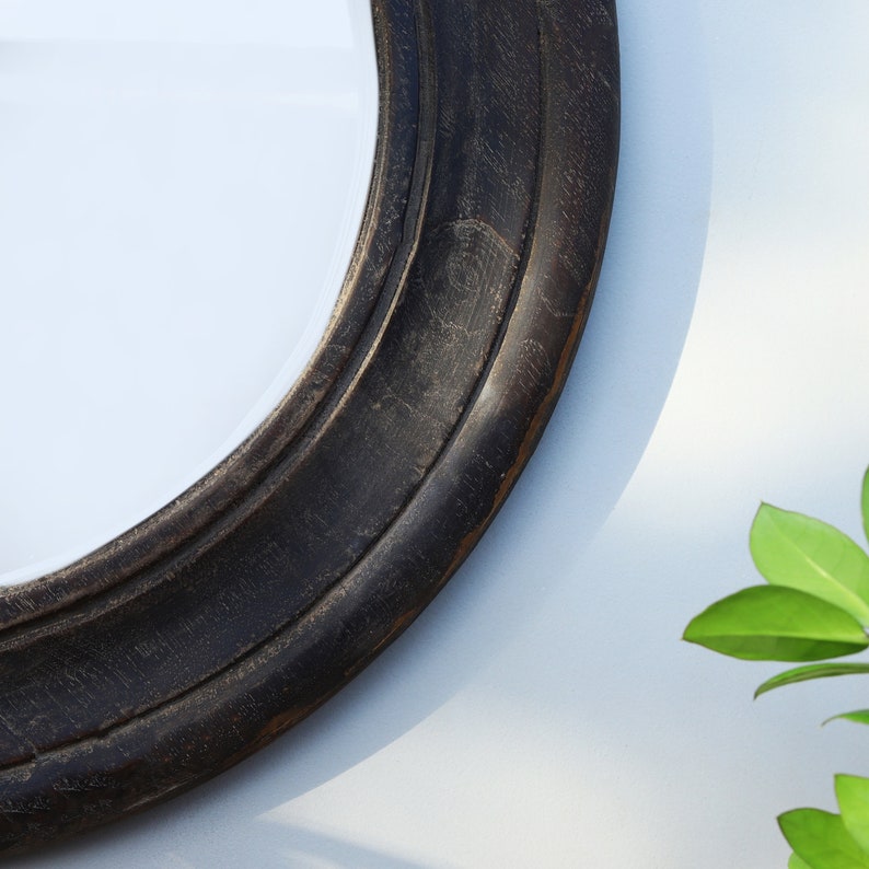 Handcrafted round mirror with a reclaimed teak wood frame and smoky black finish, featuring rounded edges and natural wood character. Rustic wall mirror for bedroom, bathroom, living room or entryway. Reclaimed teak mirror, round wooden mirror, black wood mirror, handmade wall decor, rustic home decor, sustainable wood furniture, artisan-crafted mirror.