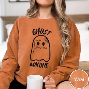 May include: A burnt orange sweatshirt with the text "GHOST MALONE" and a ghost graphic with the text "Stay Away Always Tired" on it.