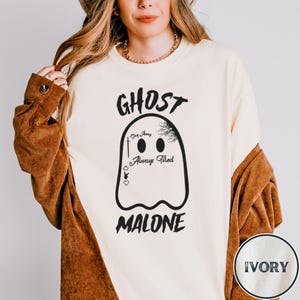 May include: A white sweatshirt with a black ghost graphic and the text "GHOST MALONE". The ghost has the words "Stay Away", "Always", and "Tired" written on it. The sweatshirt is available in ivory.