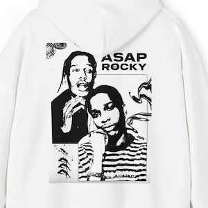 Puede incluir: Sudadera con capucha blanca con un gráfico en blanco y negro de dos personas y el texto "ASAP ROCKY". El gráfico está en la parte posterior. La sudadera tiene capucha y mangas largas.