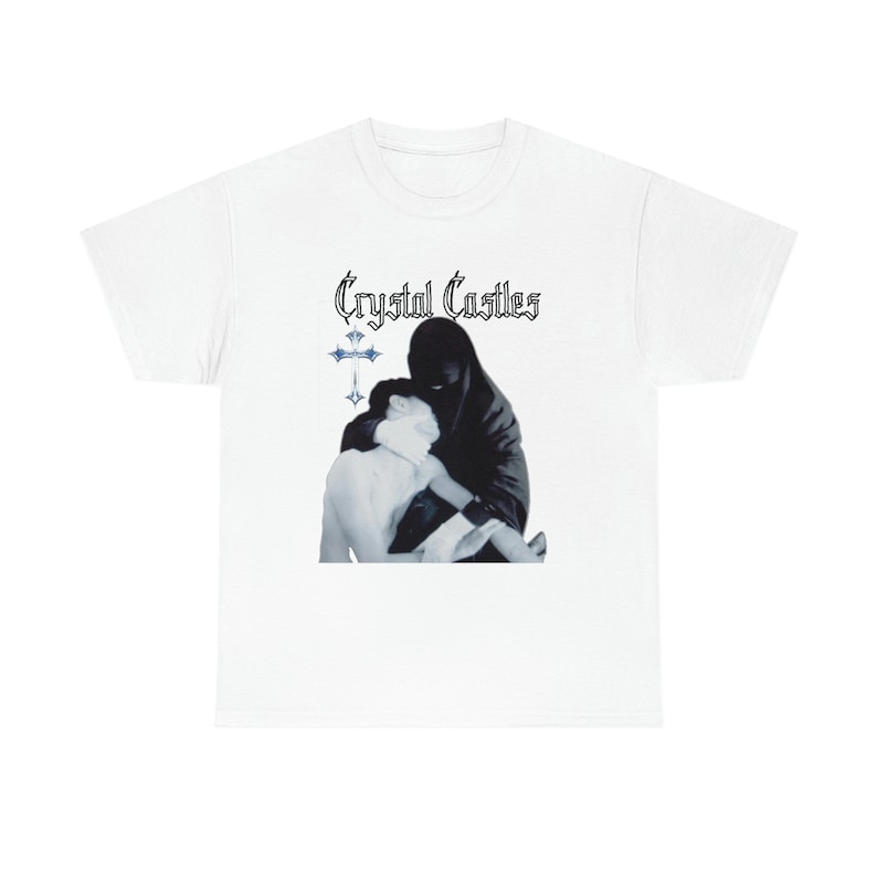 Puede incluir: Camiseta blanca con el texto "Crystal Castles" y una imagen en blanco y negro de dos personas abraz&aacute;ndose. Tambi&eacute;n hay una cruz azul en la camiseta.