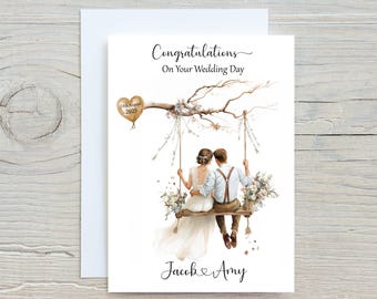 May include: A wedding greeting card with a watercolor illustration. The card features a couple on a swing, with floral accents and the text "Congratulations On Your Wedding Day." A heart-shaped balloon displays the date "16th August 2025" and the names "Jacob & Amy".