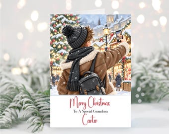 May include: A greeting card featuring a person in a brown shearling jacket, black knit hat, and scarf taking a selfie in a snowy Christmas market. The text reads Merry Christmas To A Special Grandson Carter in red and black script and print.