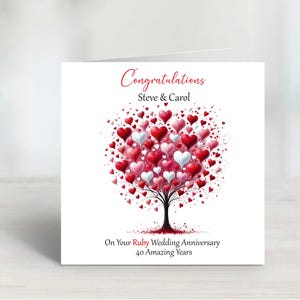 May include: A white card with a red heart tree design. The card says "Congratulations Steve & Carol On Your Ruby Wedding Anniversary 40 Amazing Years".