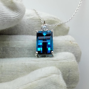 May include: A silver necklace featuring a large, rectangular, blue topaz pendant with a smaller, round, clear diamond accent.