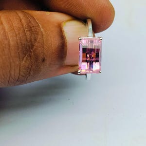 Puede incluir: Un anillo de plata con una piedra rectangular rosa.