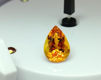 May include: A teardrop-shaped orange gemstone with a faceted cut.