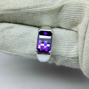 May include: A silver ring with a large, rectangular, purple amethyst gemstone.