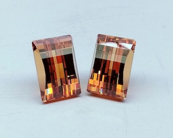 May include: Two rectangular, faceted, orange and brown gemstones with a shimmering, iridescent finish.