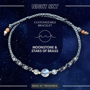 May include: A customizable bracelet with a moonstone and brass stars. The bracelet is made of gray cord and has a "Night Sky" theme. The text "Moonstone & Stars of Brass" is printed on the image.