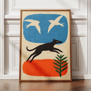 Puede incluir: Impresión artística enmarcada con un perro negro saltando sobre una forma naranja, con dos pájaros blancos sobre un fondo azul. Una planta verde también está incluida en el diseño. La obra de arte tiene una estética vintage.