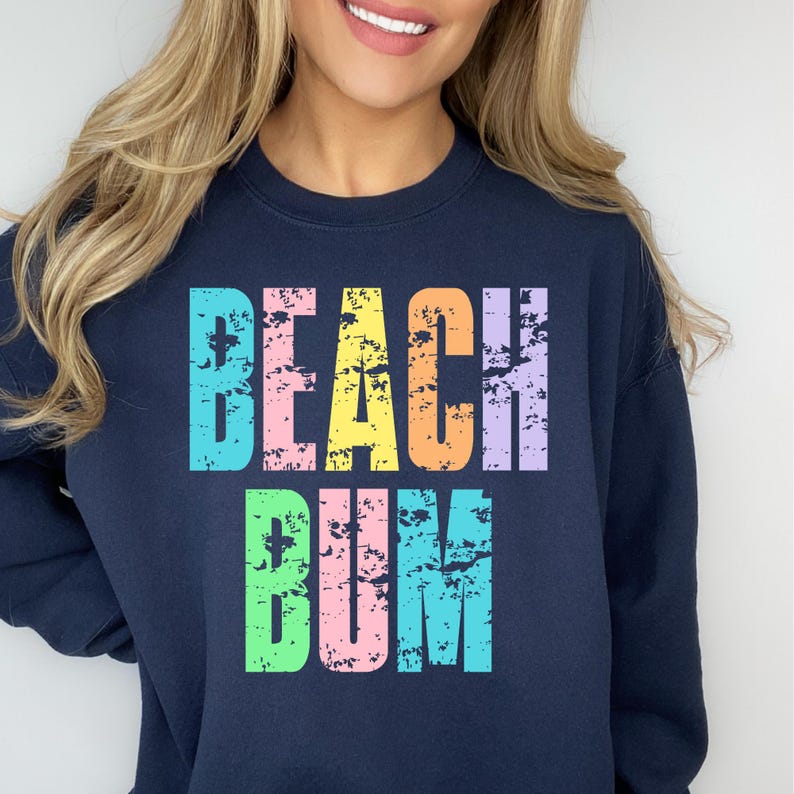 May include: A navy blue sweatshirt with the text "Beach Bum" in rainbow colors. The text is in a distressed font.