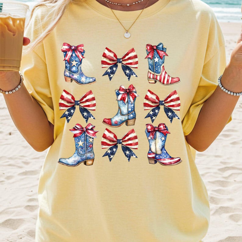 May include: A light yellow t-shirt featuring a repeating pattern of cowboy boots and bows in red, white, and blue, reminiscent of the American flag. The boots have star and stripe designs, and the bows add a decorative touch.