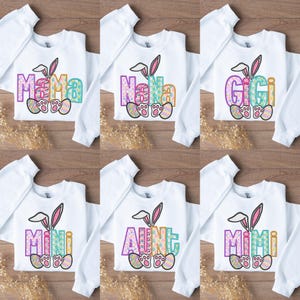 May include: Six white sweatshirts with Easter bunny ears and different names on each. The names are "Mama", "Nana", "Gigi", "Mimi", "Aunt", and "Mimi".
