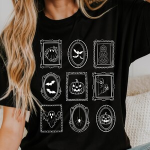 May include: Black t-shirt featuring nine white framed Halloween-themed illustrations. The designs include ghosts, bats, pumpkins, and a spider. The shirt's design is a grid of framed images, perfect for the spooky season.