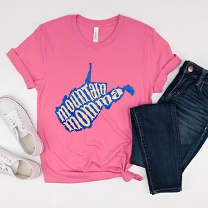 May include: Pink t-shirt with a blue outline of the state of West Virginia. The words "mountain momma" are written in a cream color inside the state outline.
