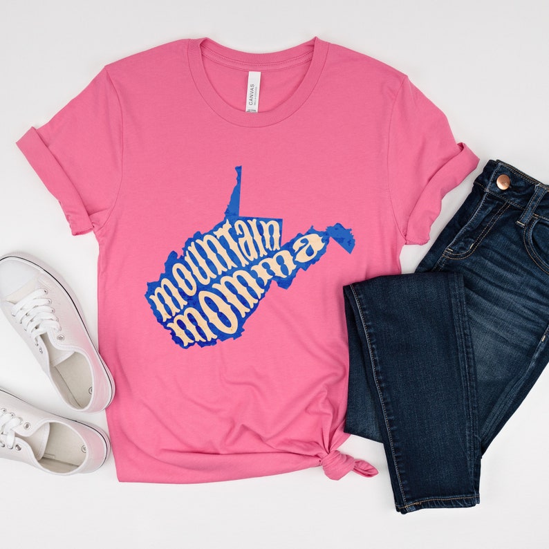 May include: Pink t-shirt with a blue outline of the state of West Virginia. The words "mountain momma" are written in a cream color inside the state outline.