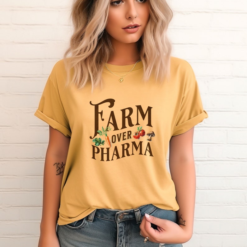 May include: A yellow short-sleeved t-shirt with the text "FARM over PHARMA" in brown lettering. The text is surrounded by a graphic of vegetables and a mushroom.