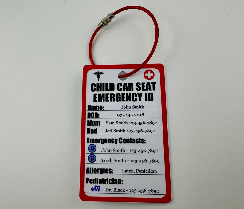 May include: Red and white child car seat emergency ID card with a metal ring. The card has the text "CHILD CAR SEAT EMERGENCY ID" and includes fields for name, date of birth, mom, dad, emergency contacts, allergies, and pediatrician.